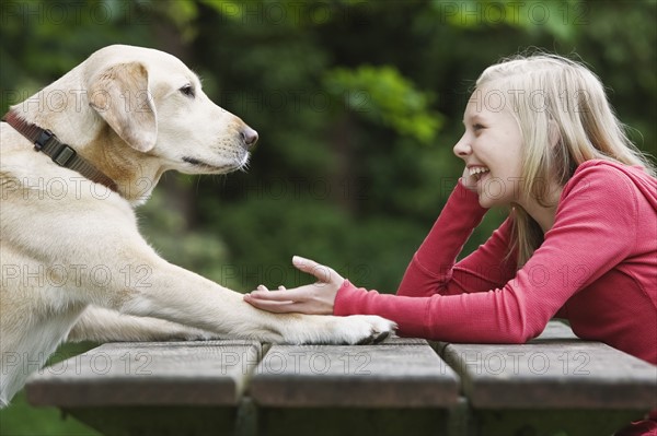 Dog sitting across from girl on picnic table. Date : 2008