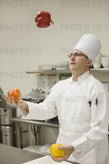Chef juggling assorted peppers. Date : 2008