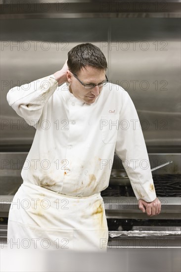 Tired chef leaning against stove. Date : 2008