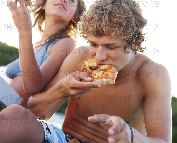 Young couple eating pizza at beach. Date : 2008