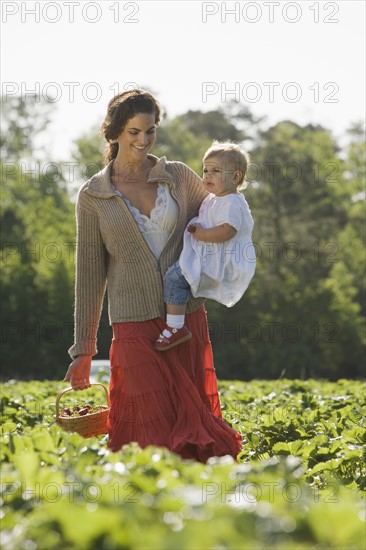 Mother and baby daughter picking strawberries. Date : 2008
