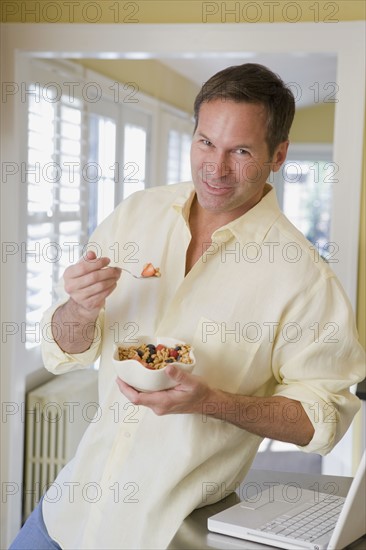 Man eating cereal in kitchen. Date : 2008