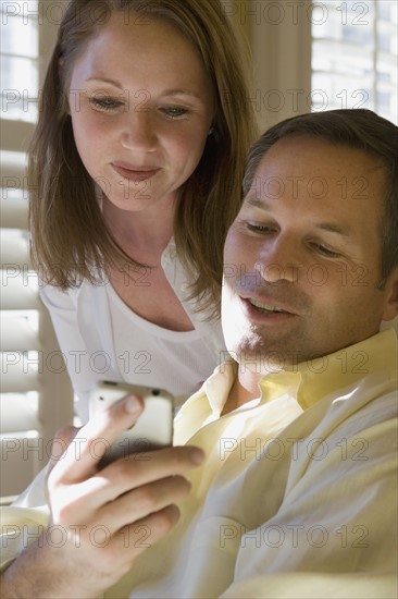 Couple looking at cell phone. Date : 2008