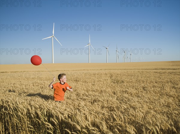 Boy running with balloon on wind farm. Date : 2008