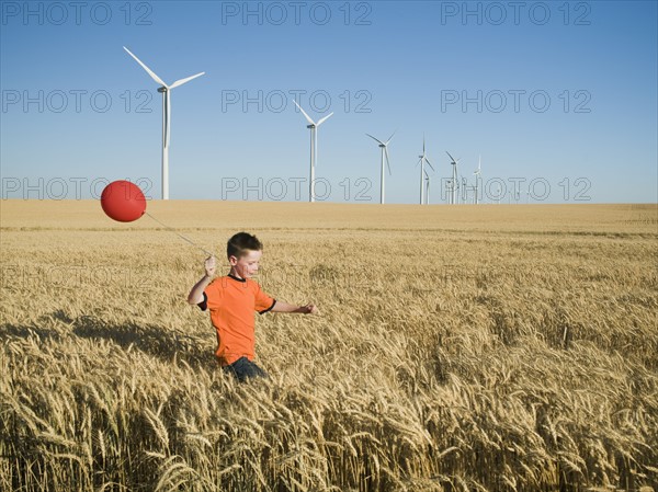 Boy running with balloon on wind farm. Date : 2008