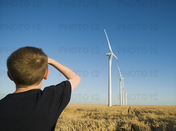 Boy looking up at windmills on wind farm. Date : 2008