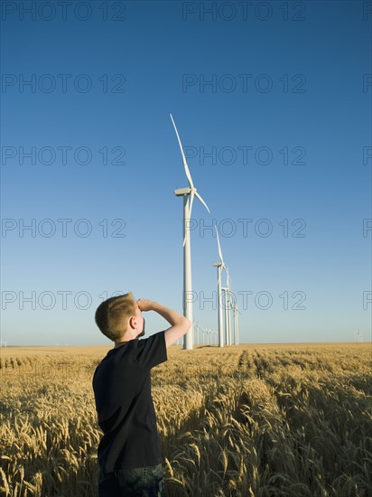 Boy looking up at windmills on wind farm. Date : 2008