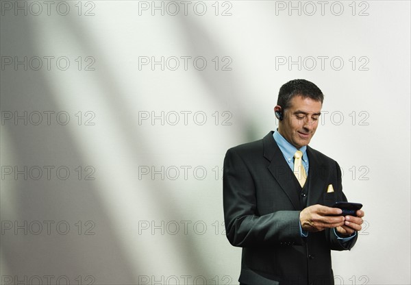 Businessman using cell phone and hands-free device. Date : 2008