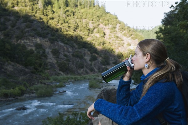 Young woman drinking water on river overlook. Date : 2008