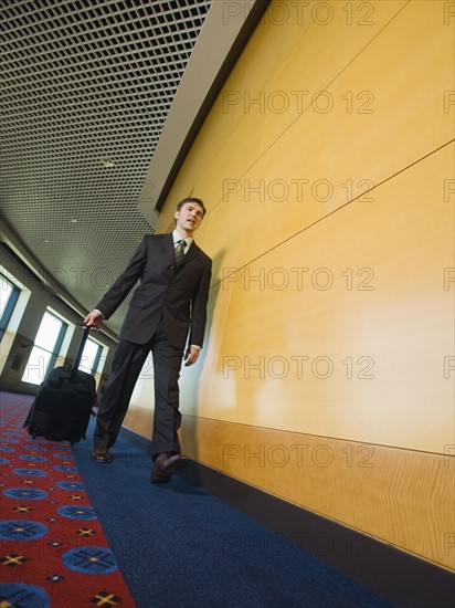 Businessman pulling suitcase in office corridor. Date : 2008