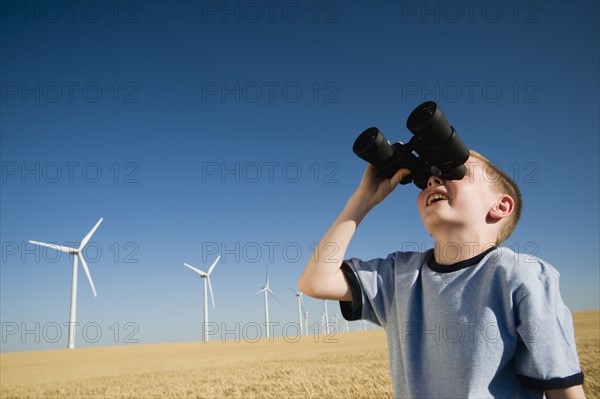 Boy on wind farm looking through binoculars. Date : 2008