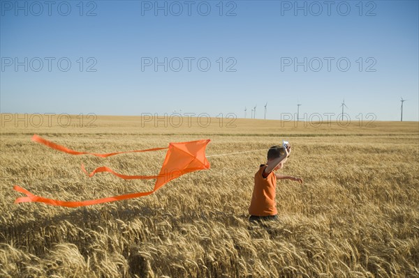 Boy running with kite on wind farm. Date : 2008