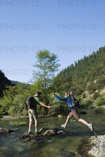 Hikers jumping across river on rocks. Date : 2008