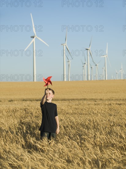 Boy holding pinwheel on wind farm. Date : 2008