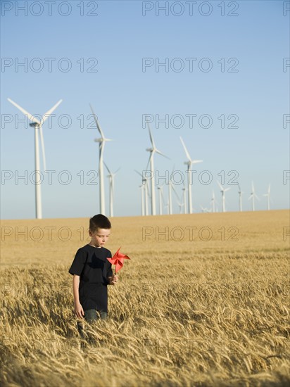 Boy holding pinwheel on wind farm. Date : 2008