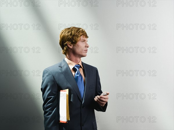 Businessman holding cell phone and files. Date : 2008