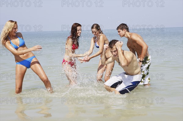 Friends splashing each other in ocean. Date : 2008