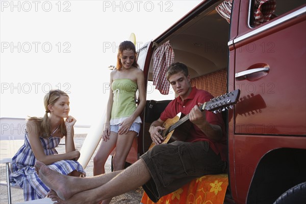 Friends socializing around van on beach. Date : 2008