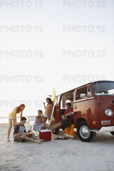 Friends socializing around van on beach. Date : 2008