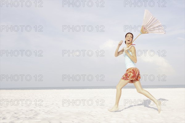 Girl running on beach with umbrella. Date : 2008