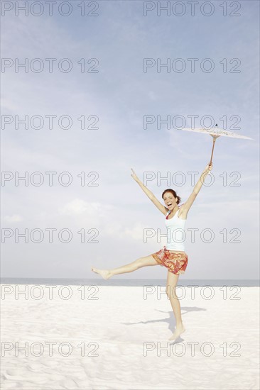 Girl holding umbrella and dancing on beach. Date : 2008