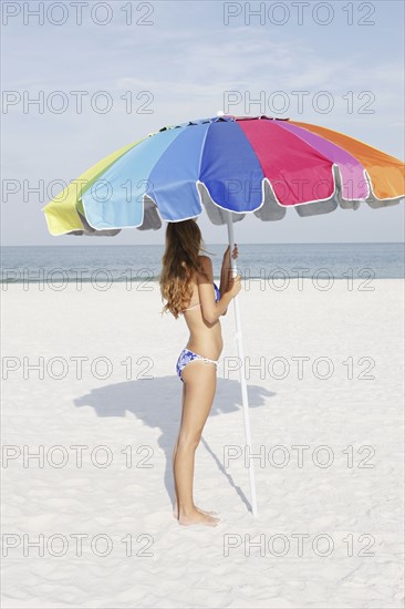 Teenage girl holding umbrella on beach. Date : 2008