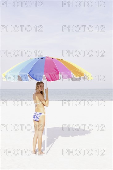 Teenage girl holding umbrella on beach. Date : 2008