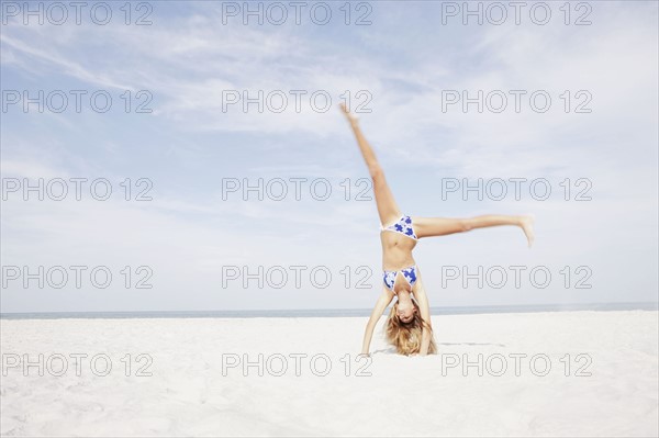 Teenage girl doing cartwheel in beach. Date : 2008