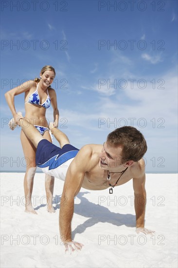 Teenage girl pushing boyfriend on beach. Date : 2008