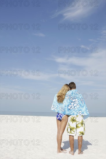 Teenage couple sharing towel on beach. Date : 2008