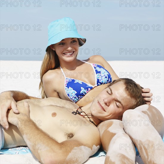 Young couple leisurely sunbathing on beach. Date : 2008