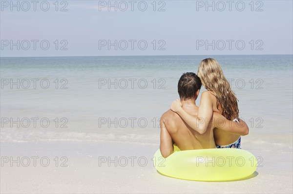 Couple sitting in inflatable ring in shallow ocean. Date : 2008