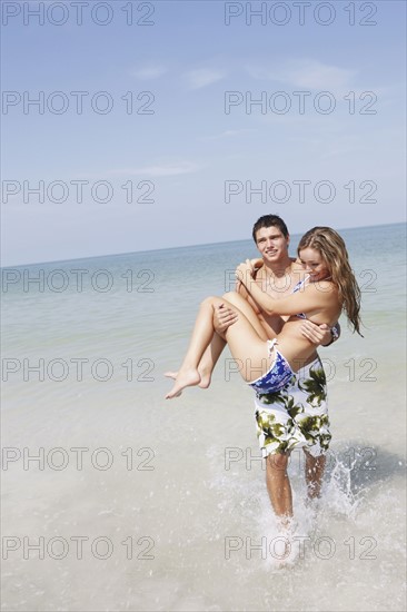 Teenage boy carrying girlfriend in ocean. Date : 2008