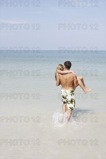 Teenage boy carrying girlfriend in ocean. Date : 2008