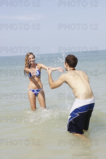 Teenage couple splashing each other in ocean. Date : 2008