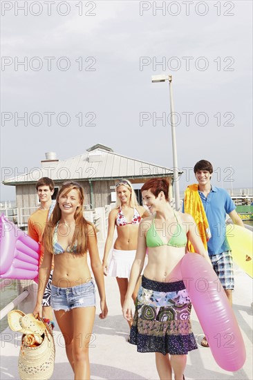 Friends carrying beach essentials on boardwalk . Date : 2008