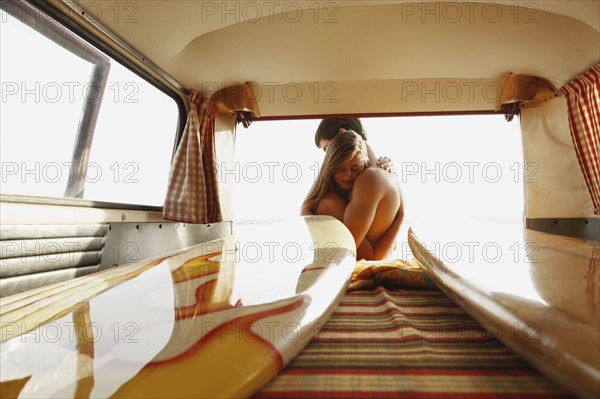 Teenage surfers hugging by van. Date : 2008