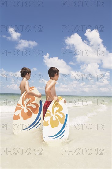 Boys holding skimboards in ocean. Date : 2008