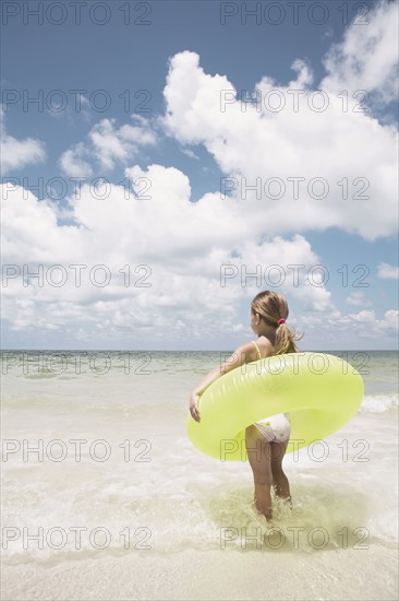 Girl carrying inflatable ring into ocean. Date : 2008