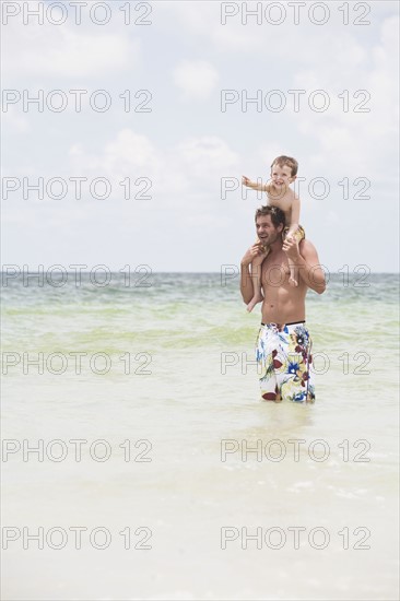 Father carrying son on shoulders in ocean. Date : 2008