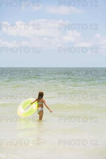 Girl carrying inflatable ring into ocean. Date : 2008