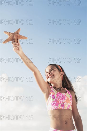 Girl in bathing suit holding up starfish. Date : 2008