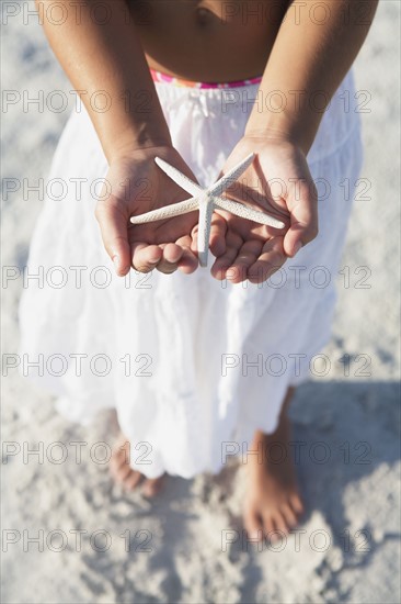 Girl on beach holding delicate starfish. Date : 2008