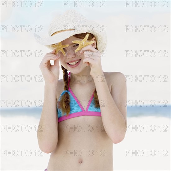 Girl on beach holding starfish. Date : 2008