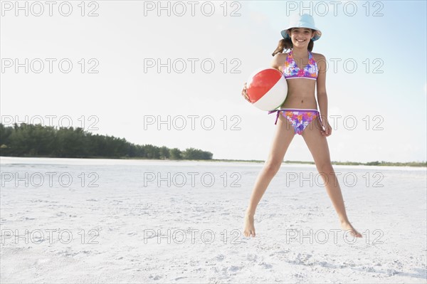 Girl jumping on beach with beach ball . Date : 2008
