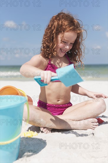 Girl digging in sand on beach. Date : 2008
