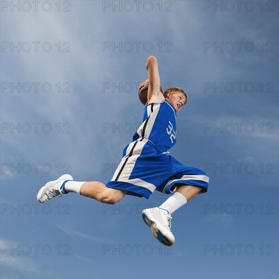 Teenage basketball player in mid-air throwing basketball. Date : 2008