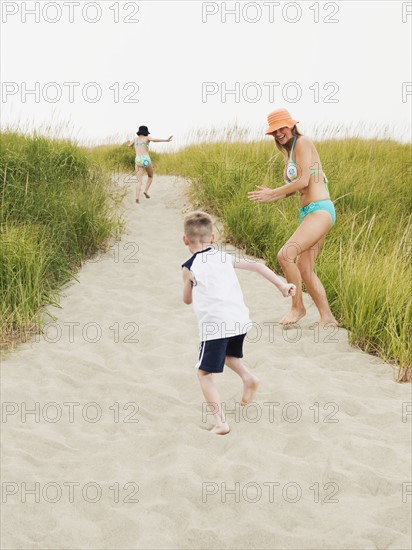 Mother running on beach with daughter and son. Date : 2008