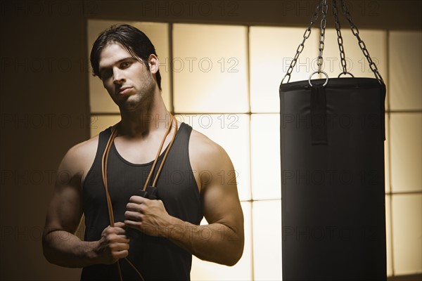 Man with jump rope posing by punching bag. Date: 2008