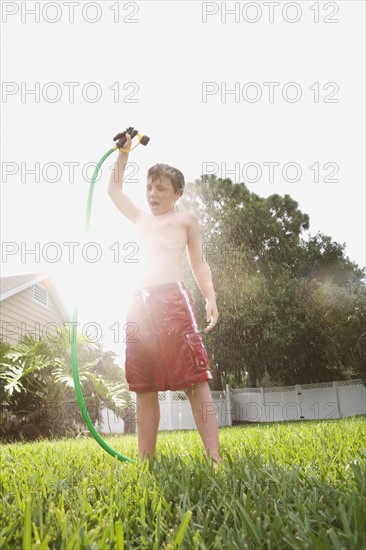 Boy spraying himself with hose in backyard. Date : 2008